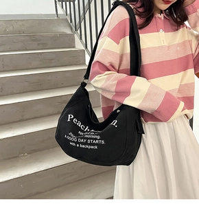 Détail du sac bandoulière en toile noire avec impression de lettres et grande capacité