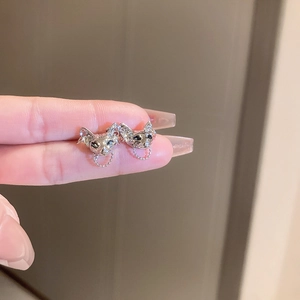 Detail of silver cat-shaped studs with dangling chain tassels held by a hand