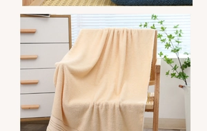 Close-up of soft beige cotton bath towel with gold stripes draped over a wooden chair