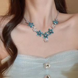 Gros plan d'un collier floral avec zircons bleus et blancs porté par un modèle