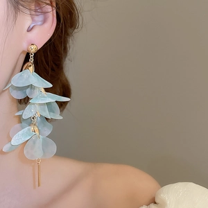 Gros plan de boucles d'oreilles fleurs en tulle bleu portées par un mannequin femme