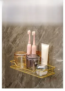 Close-up of golden wall-mounted rack holding toothbrushes against marble backdrop