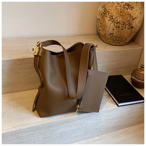 Deep brown lychee pattern tote bag with golden buckle and matching pouch on stone stairs