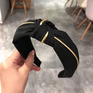 Elegant wide black knotted headband featuring golden tube accents for a chic hair accessory