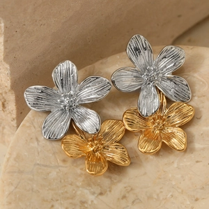 Elegante gold-silberne Ohrringe in Blumenform auf natürlichem Steinhintergrund