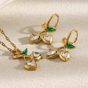Close-up of gold cherry necklace and earrings with heart-shaped white crystals