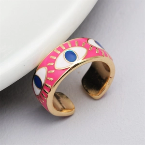 Macro detail of adjustable gold plated evil eye ring with pink enamel and blue eye motif