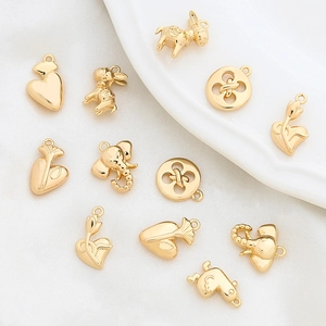 Gold-plated elephant and heart charms set for DIY jewelry making on white textured background