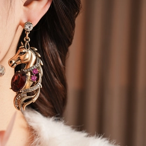 Détail d'une boucle d'oreille cheval vintage avec pierre violette et cristaux sur mannequin
