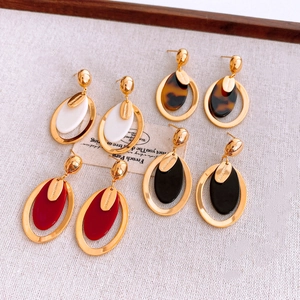 Détail de boucles d'oreilles ovales en résine blanche, écaille, rouge et noire avec tags
