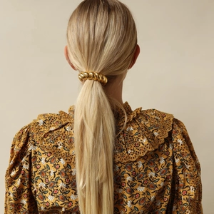 Élastique cheveux torsadé doré en métal porté en queue de cheval pour un style rétro chic
