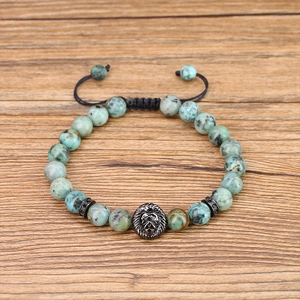 Top view of 8mm turquoise stone bracelet with a lion head charm on wooden background