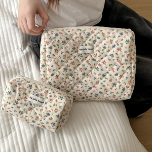Detailed macro of two floral quilted corduroy cosmetic bags with zipper and brand label