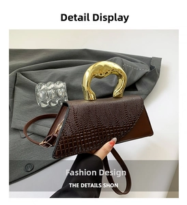 Detailed view of dark brown triangle bag with crocodile pattern and gold metal handle