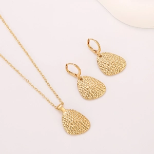 Detail of gold teardrop jewelry set with hammered texture on necklace and earrings