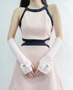 Close-up of pink ribbed knit arm sleeves with white silk bows and heart charm details