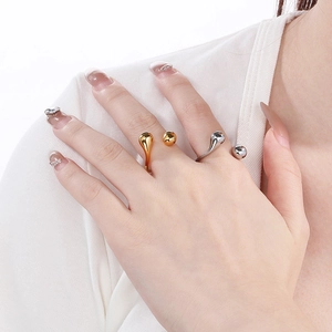 Close-up of gold and silver teardrop open rings on model's hand for luxury style