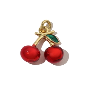 Macro shot of red cherry fruit pendant with gold metal ring and green leaves