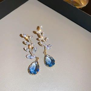 Vue détaillée de boucles d'oreilles dorées avec cristaux et pierres bleues en goutte