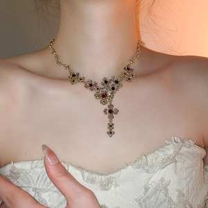 Detail of vintage gold necklace with red gemstones worn on model neck for elegant style