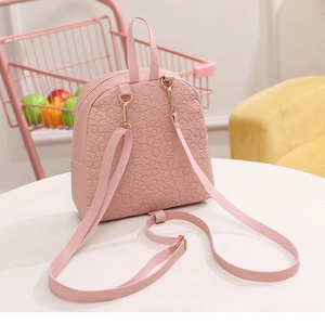Detail view of pink PU leather mini backpack featuring floral embossing and metal hardware