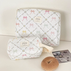 Détail des trousses de toilette matelassées à fleurs avec motifs nœuds et dragonnes