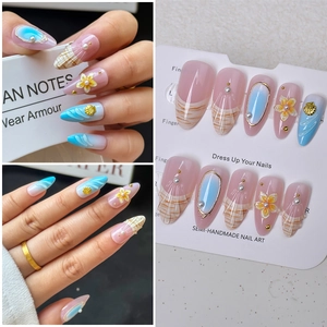 Detail of almond-shaped nails with 3D white flowers, pearls, and sea shell accents
