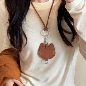 Detailed view of a brown leather cat-shaped necklace and card holder on white fabric