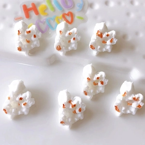 Detailed view of seven realistic white and orange resin popcorn charms for DIY crafts