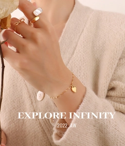 Golden heart pendant bracelet with bow and pearl rings on model in a soft aesthetic setting