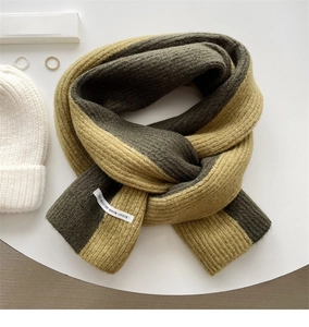Flat lay of a yellow and green knit scarf with a white beanie and elegant accessories