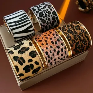 Golden wide cuffs with leopard and zebra flocking texture on a grey display stand