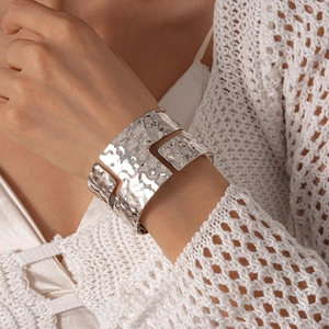 Detailed view of hammered silver metal texture and cutout design on wide open cuff bracelet