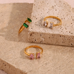 Detailed view of three gold open rings featuring green, white, and pink rectangular gemstones