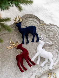 Close-up of velvet reindeer ornaments in navy, red, and white with glittery antlers