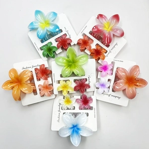 Three-piece plumeria flower hair claw set in vibrant gradient colors on display card