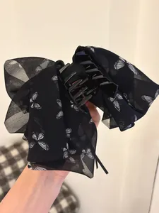 Detail of large black chiffon hair claw clip with white butterfly print and flowing ribbons