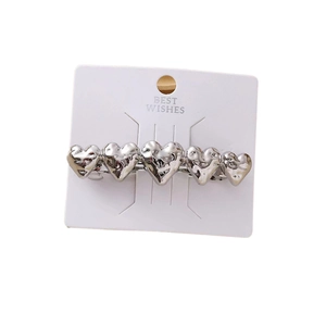 Silver zinc alloy hair clip with five linked hearts and hammered texture on white card