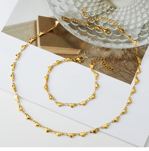 Detail of gold heart link necklace and bracelet set with lobster clasp on white background