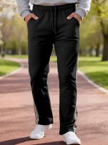 Close-up of black men's joggers with side stripe design on an outdoor running track