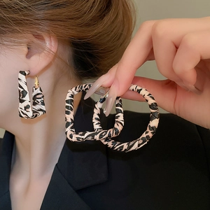 Close-up of leopard print faux leather hoop earrings with intricate woven texture