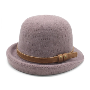 Detailed close-up of purple knitted bowler hat with brown leather strap and gold rivets
