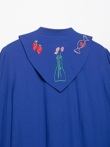 Detailed embroidery of strawberry and floral patterns on textured blue hooded jacket