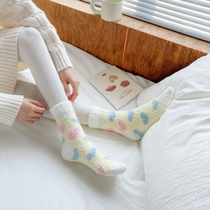 Detailed texture of thick coral fleece socks with colorful polka dots in cozy bedroom setting