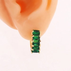 Close-up of minimalist gold hoop earring with emerald green cubic zirconia on ear