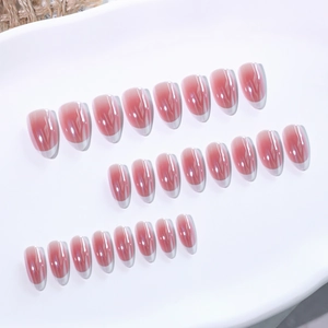 Pink blush almond press-on nails with white French tips set on a ceramic tray