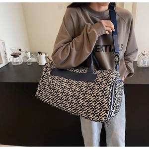 Dettaglio della borsa da viaggio stampata con motivo geometrico e pelle blu sul modello