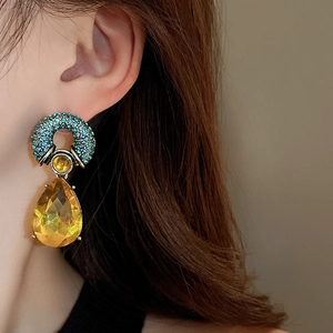 Detail of luxury teardrop earrings with yellow faceted crystals and blue micro-pave