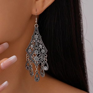 Detailed view of vintage silver hollow flower drop earrings with ethnic tassels on model