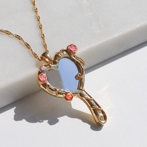 Detail of magic mirror necklace with heart glass and pink rose carvings in gold finish